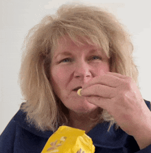 a woman is eating a snack from a bag that says peanuts on it