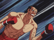 a shirtless boxer wearing red boxing gloves looks angry