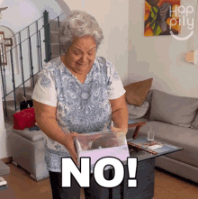 an elderly woman holding a box that says no on it