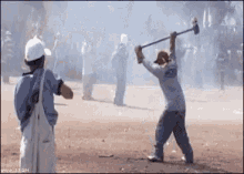 a man is swinging a hammer at another man in a crowd of people .