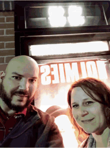 a man and a woman are standing in front of a sign that says 21mile