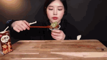 a woman is eating a spoonful of food next to a box that says gold