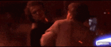 a man is standing in front of a burning room with a woman laying on a bed .