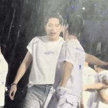 a couple of men are standing next to each other in the rain on a stage .