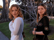 two women standing next to each other with one wearing a black top