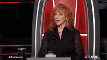 a woman is sitting in a chair with a nbc logo on the bottom