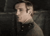 a man in a military uniform is standing in a dark room and looking at the camera .