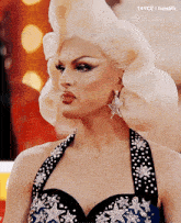 a woman in a wig and earrings is wearing a black and blue dress .