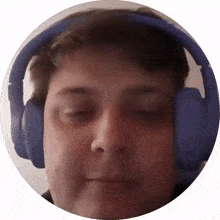 a man wearing blue headphones looks at the camera with his eyes closed