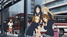 a group of anime girls are posing for a picture in front of a bus stop with the number 5 on it