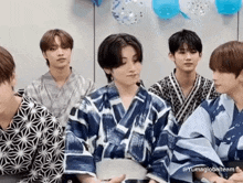 a group of young men in kimonos are sitting next to each other .