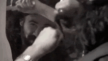 a man with a beard is holding a woman 's hand in front of his face in a black and white photo .