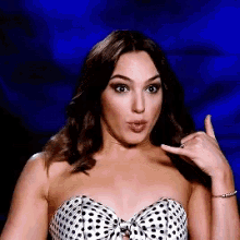 a woman in a polka dot strapless top is making a call me gesture