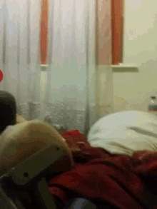 a person laying on a bed with a red blanket on it