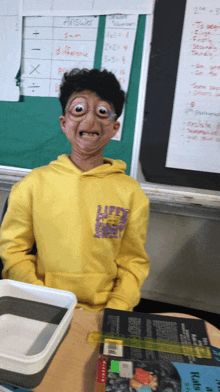 a boy wearing a yellow sweatshirt with the word left on it makes a funny face