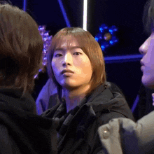 a man with long brown hair is standing in a crowd of people .