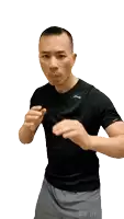 a man wearing a black shirt and grey shorts is standing in a boxing pose