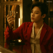 a man in a red jacket holds a glass in his hand