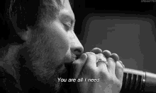 a black and white photo of a man singing into a microphone with the words you are all i need written below him