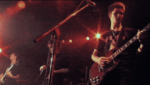 a man playing a guitar in front of a microphone with a shirt that says ' ox ' on it