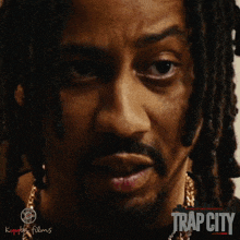 a close up of a man 's face with the word trap city on the bottom