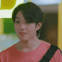 a young man is wearing a pink shirt and a black strap