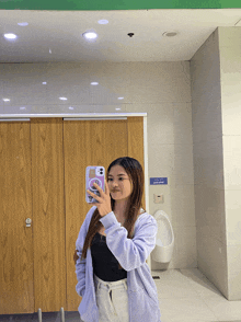 a woman taking a selfie in a public bathroom