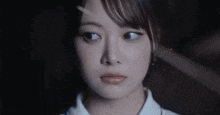 a close up of a woman 's face in a dark room with a blurred background .