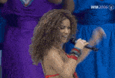 a woman in a red bikini singing into a microphone with wm 2006 in the corner