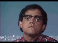 a man wearing glasses and a plaid shirt is making a face