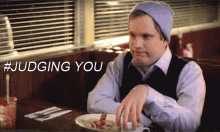 a man is sitting at a table with a plate of food and the words # judging you written above him