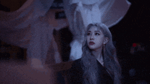 a woman with gray hair and earrings looks up at something