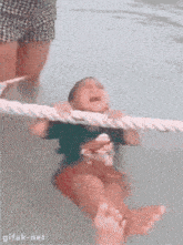 a baby is crying in a swimming pool with a rope around his neck