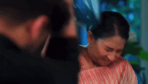 a man and a woman are sitting next to each other in a room and the woman is crying .