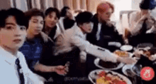 a group of young men are sitting around a table with plates of food .