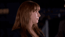 a woman with red hair is smiling and wearing a black shirt