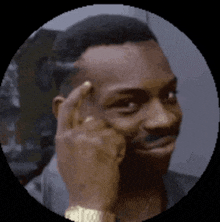 a man with his finger on his forehead is wearing a watch