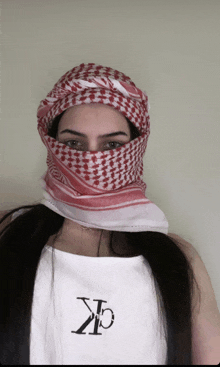 a woman wearing a red and white scarf around her face and a white shirt with the letters ck on it