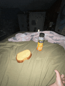 a bottle of sunkist orange juice sits on a bed next to a piece of bread