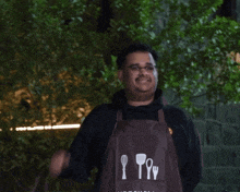 a man wearing a kitchen apron is giving an ok sign
