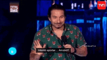 a man in a green shirt is standing in front of a microphone and talking into it .