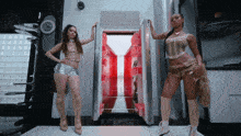two women standing in front of a refrigerator with the door open