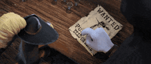 a person is writing on a piece of paper that says wanted on it