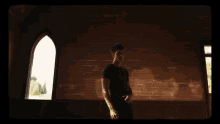 a man in a black shirt is standing in front of a window
