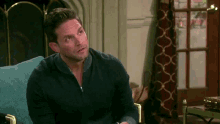 a man in a blue sweater is sitting in a chair in a living room