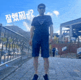 a man wearing a guess t-shirt and shorts is standing on a sidewalk