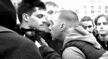 a black and white photo of two men standing next to each other in a crowd of people .