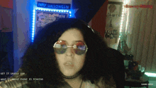 a woman wearing sunglasses stands in front of a wall that says happy halloween
