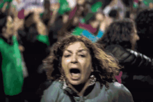 a woman is screaming in front of a crowd of people wearing green shirts