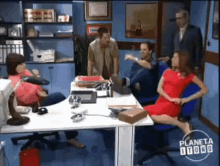 a woman in a red dress sits at a desk with her legs crossed in front of a man in a suit and another man